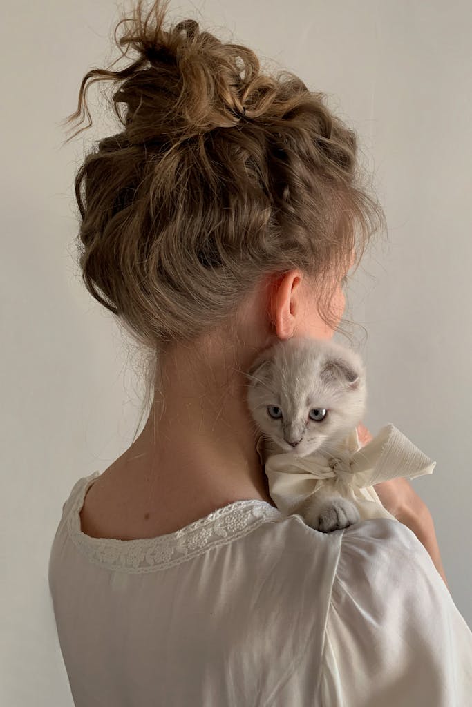 Young woman in Paris holds a kitten with a bow, showing a gentle bond.